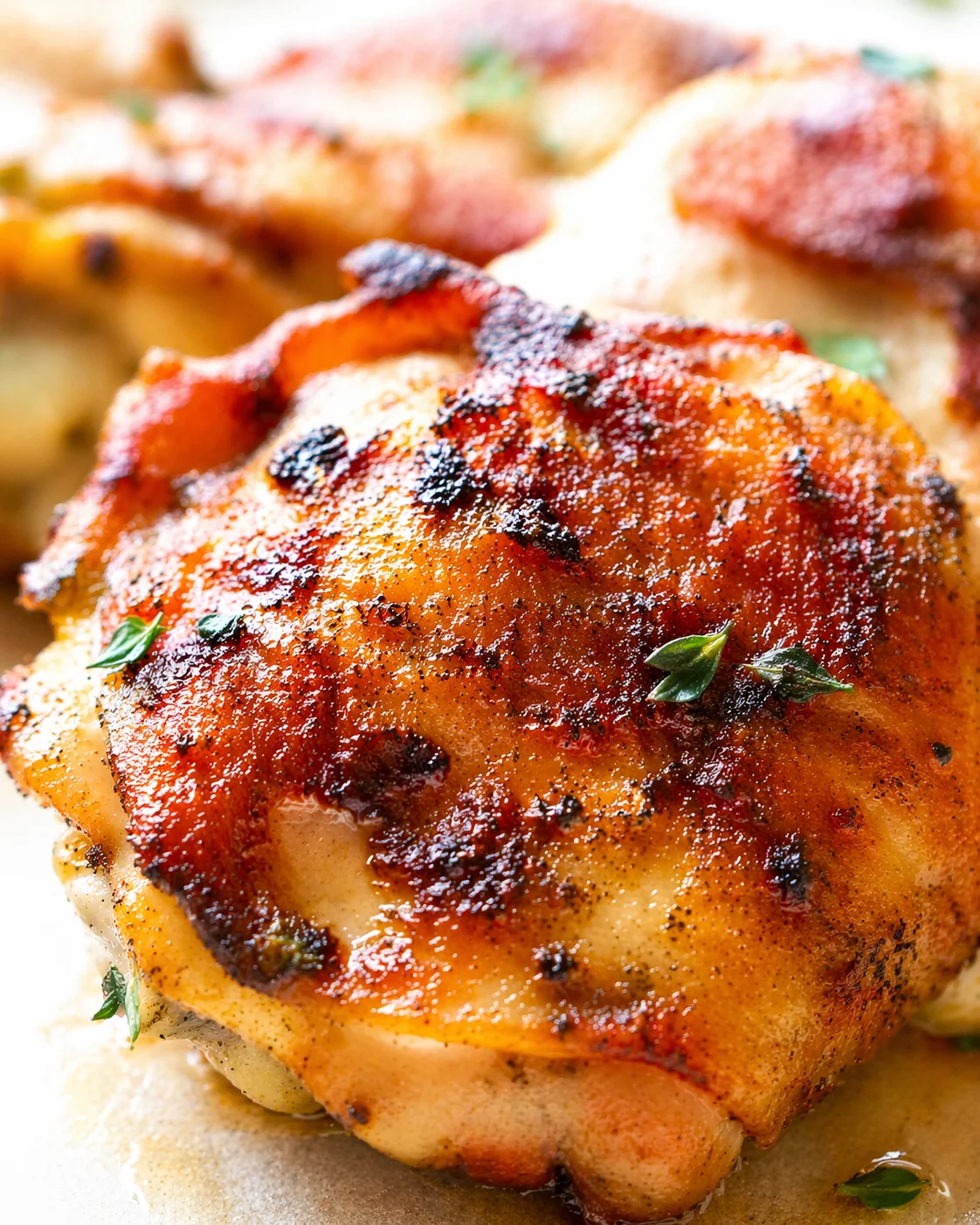 close-up of crispy roasted chicken thigh with browned skin and herb garnish