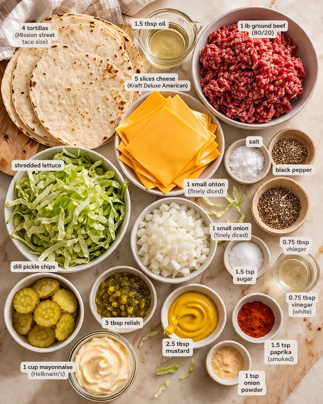 Top-down layout of taco ingredients: tortillas, ground beef, cheese slices, lettuce, onions, pickles, and condiments.