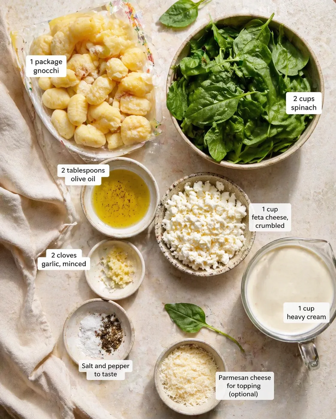 Overhead view of gnocchi, spinach, cheeses, and creams laid out for a recipe.