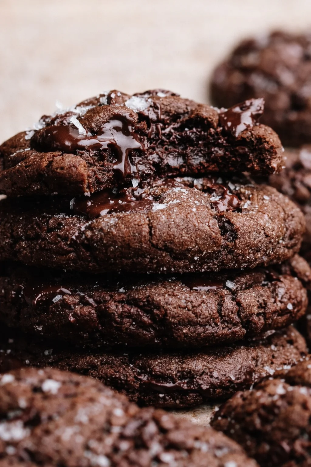 Stack of fudgy dark chocolate cookies with oozing center and sea salt.