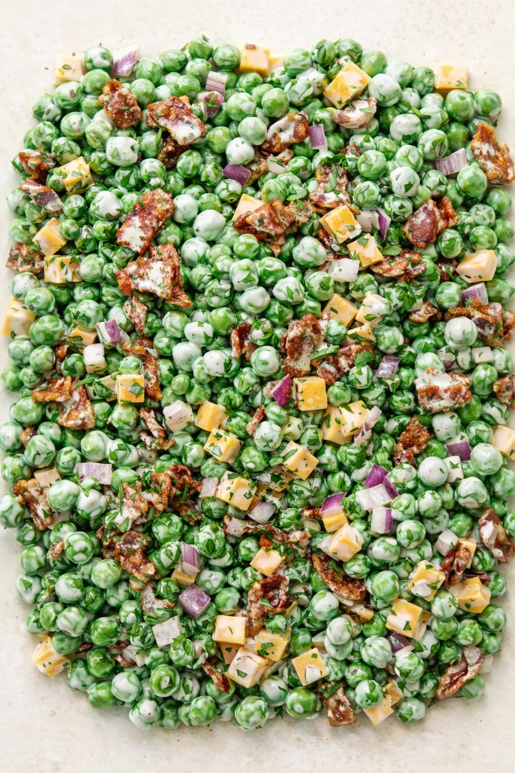 sheet pan of green peas with cheddar cubes, bacon, red onion, and herbs