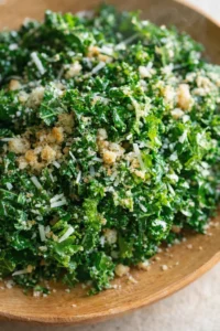 close-up of kale salad with parmesan shavings and breadcrumbs in a wooden bowl