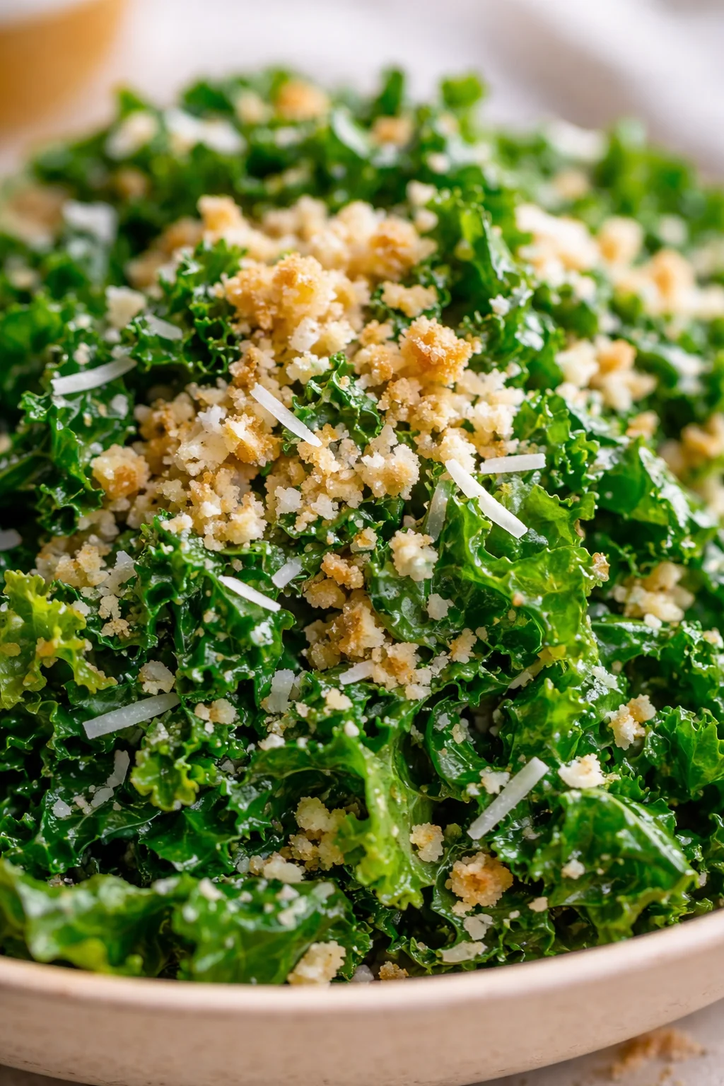 Close-up of kale salad with parmesan shavings and breadcrumbs in a wooden bowl