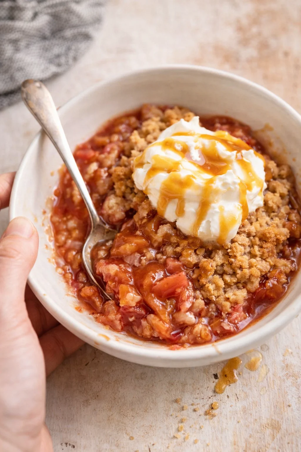 Peach crumble with whipped cream and caramel in a white bowl