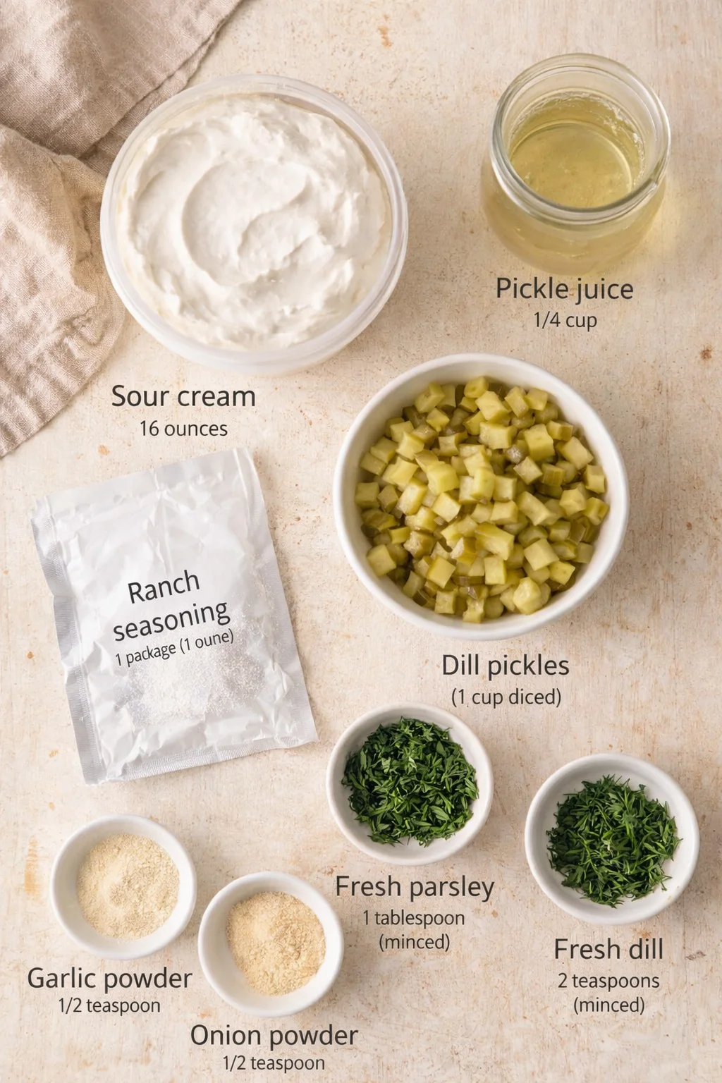 Overhead view of ranch-dressing ingredients laid out on a light-beige surface with sour cream, pickle juice, diced dill pickles, ranch seasoning, and spice powders and herbs.