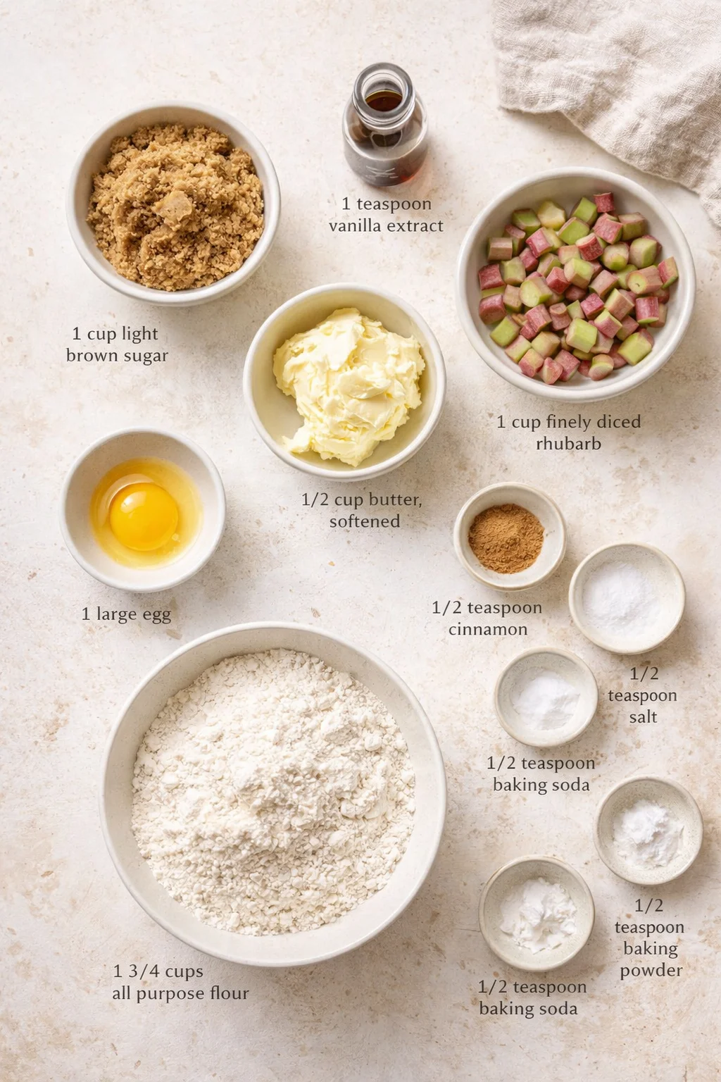 top-down view of baking ingredients arranged in bowls, including rhubarb, flour, butter, egg, and sugar
