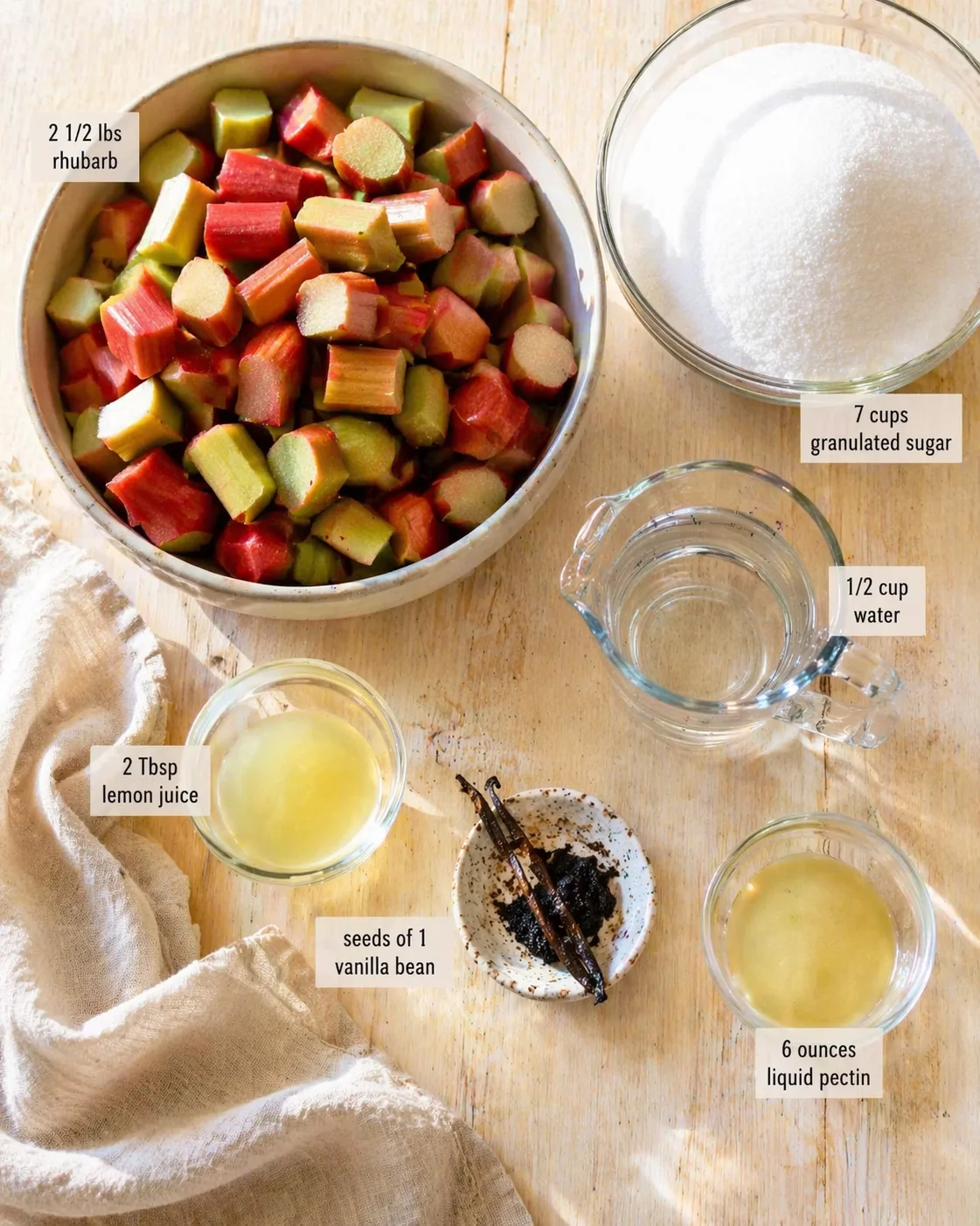 Chopped rhubarb in a metal bowl with sugar, lemon juice, vanilla seeds, and pectin.