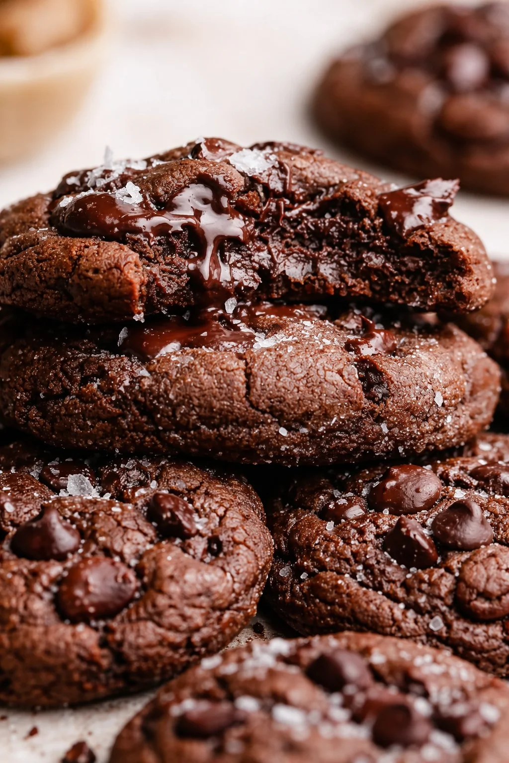 Close-up of stacked salted dark chocolate cookies with melted centers and visible sea salt.