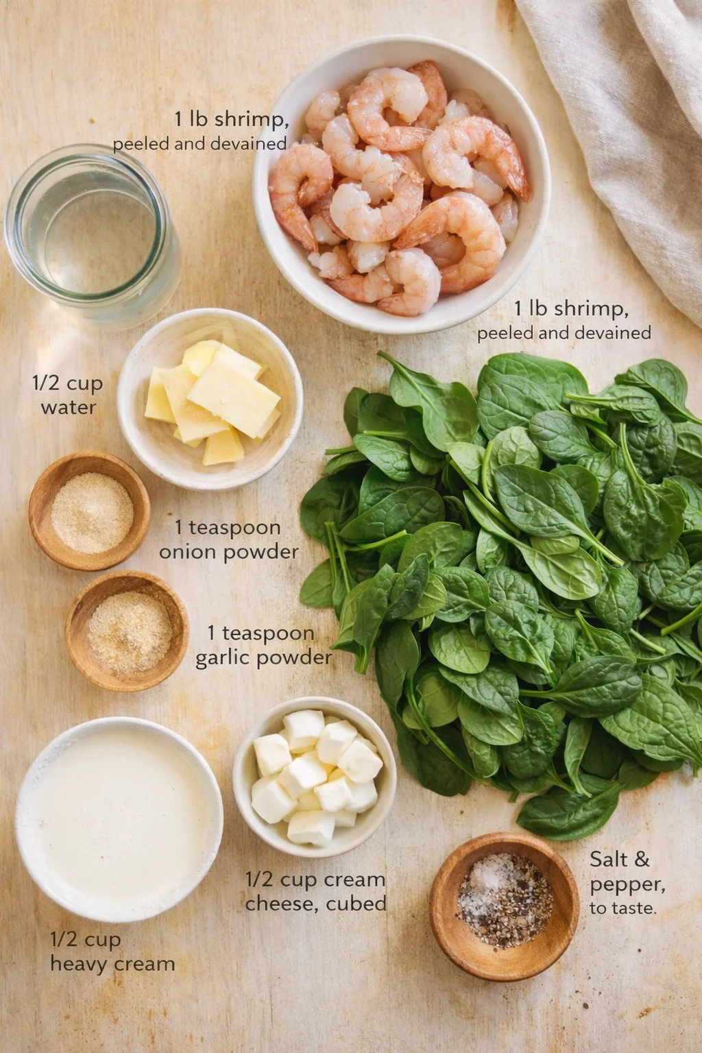 Top-down view of shrimp, spinach, and dairy ingredients arranged on a wooden surface.