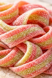 Close-up of pink and lime-yellow sugar-coated candy twists piled together.