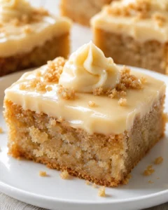 Close-up of a buttercream-frosted cake slice with crumb topping on a white plate.