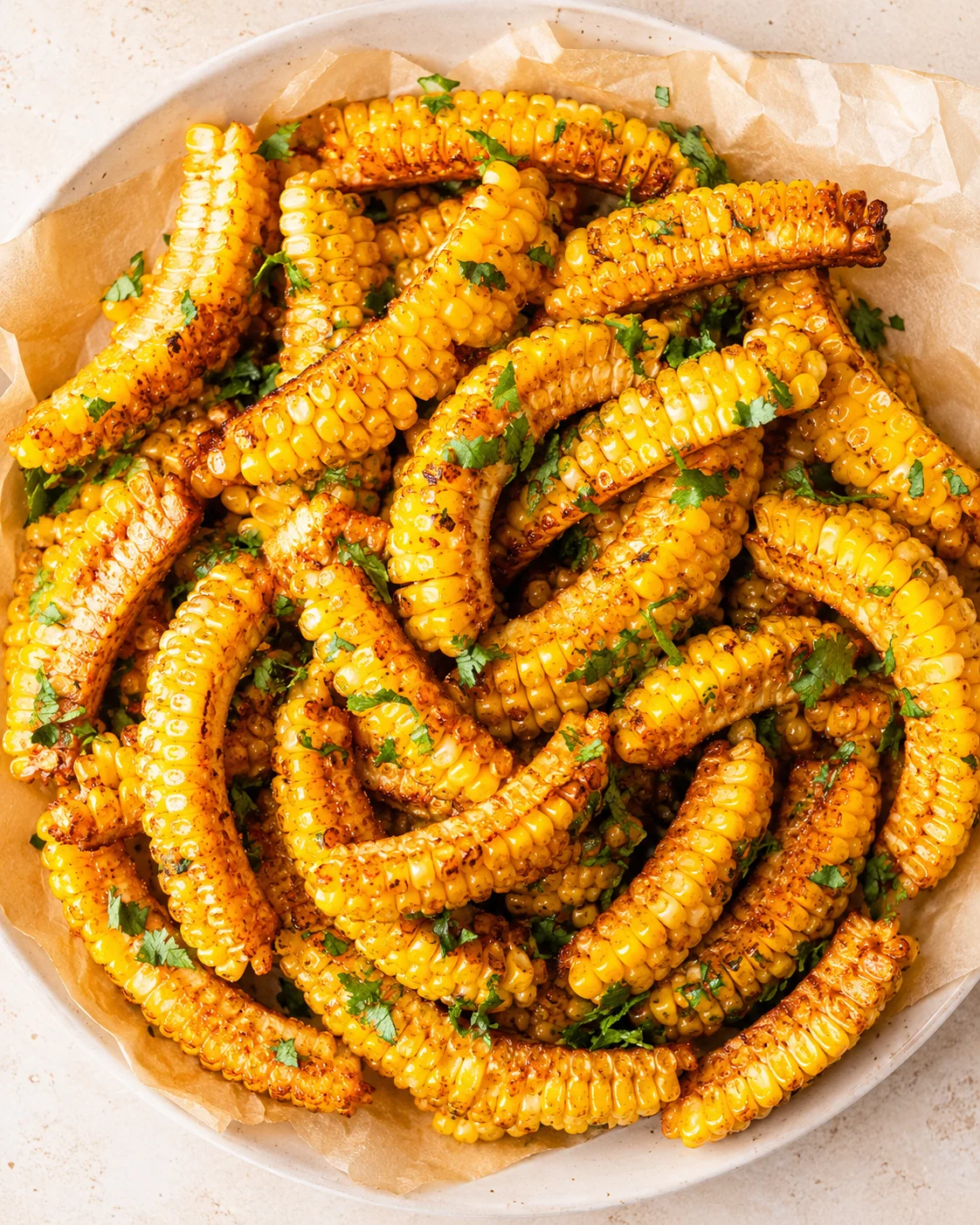 golden-yellow charred corn on the cob with chopped parsley garnish
