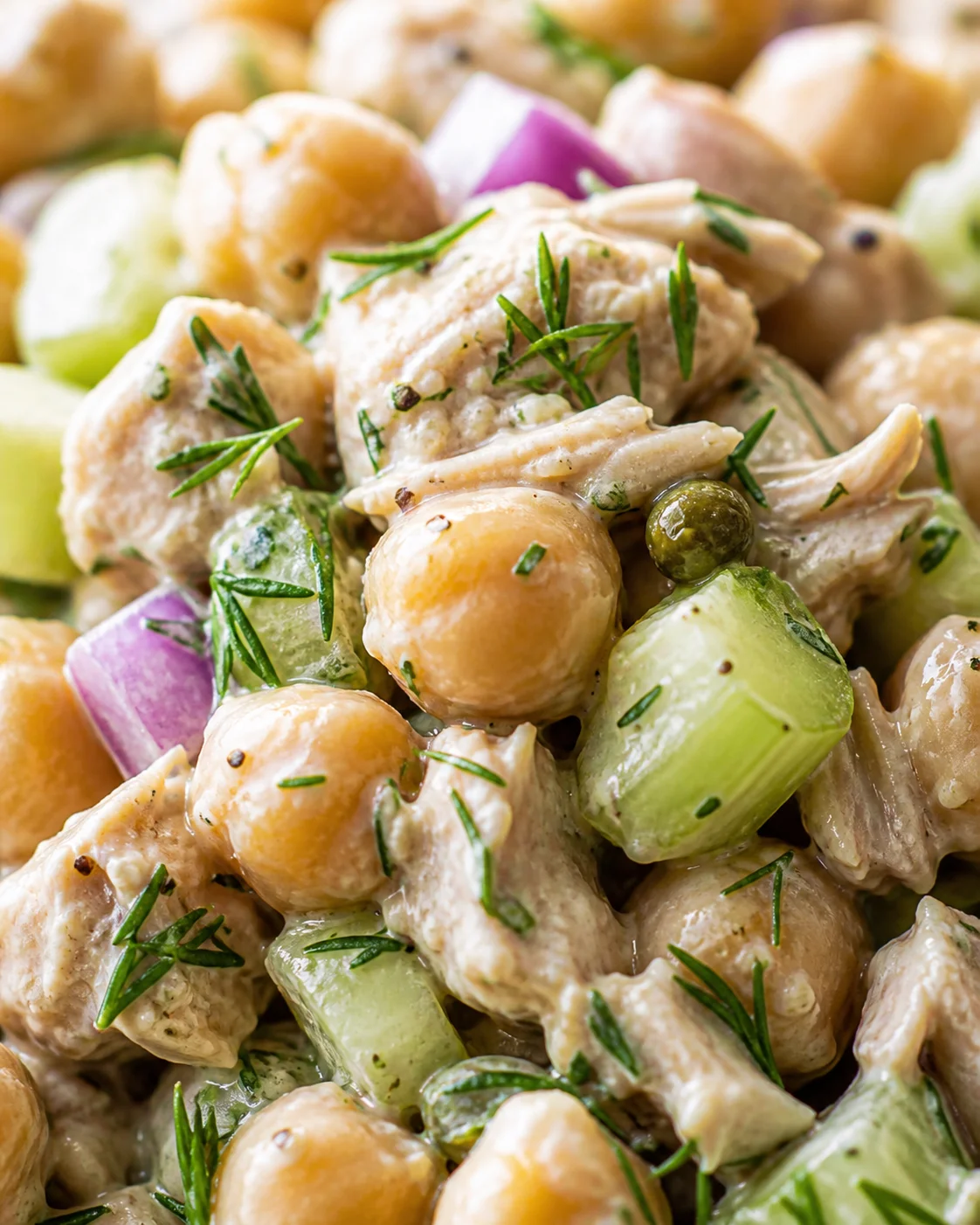 close-up of creamy chicken and chickpea salad with cucumber chunks, red onion, and dill