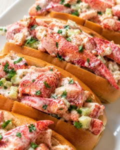 Lobster rolls with creamy mayo dressing, celery, and parsley on toasted buns.