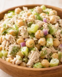 wooden bowl of creamy tuna chickpea salad with cucumber and dill garnish