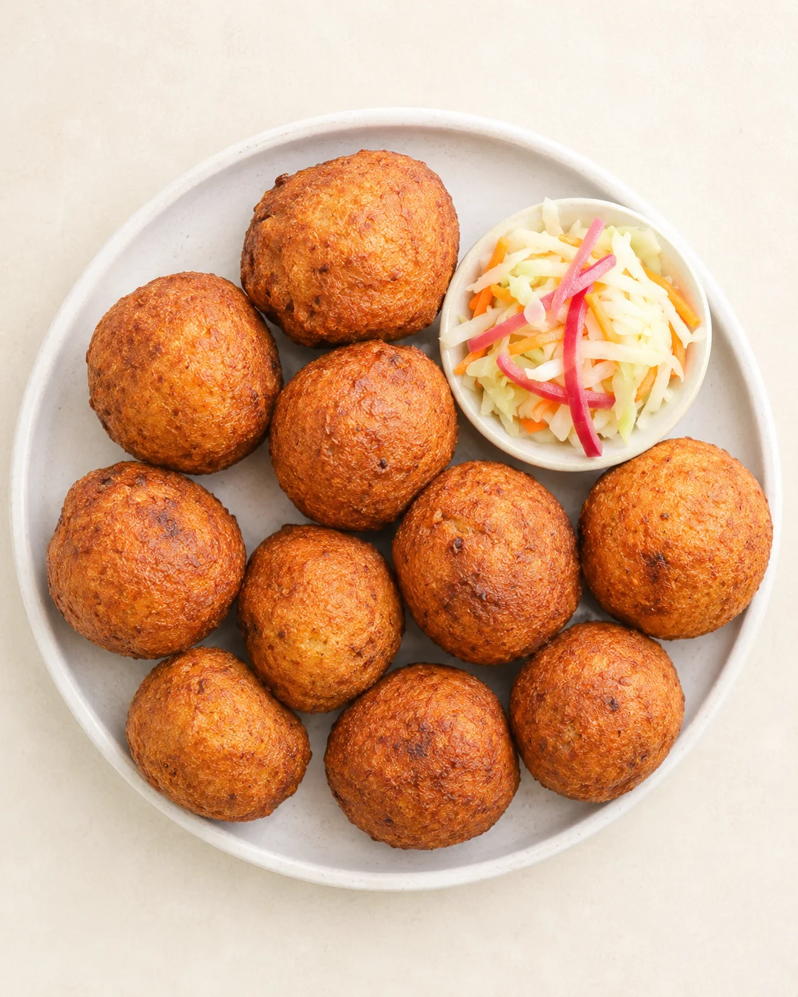 Top-down view of golden-brown croquettes on a plate with a side slaw.