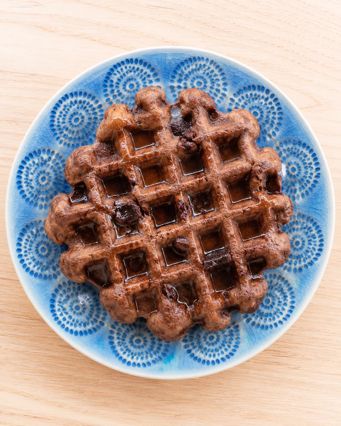 rich brown chocolate waffle on a blue patterned plate photographed from above
