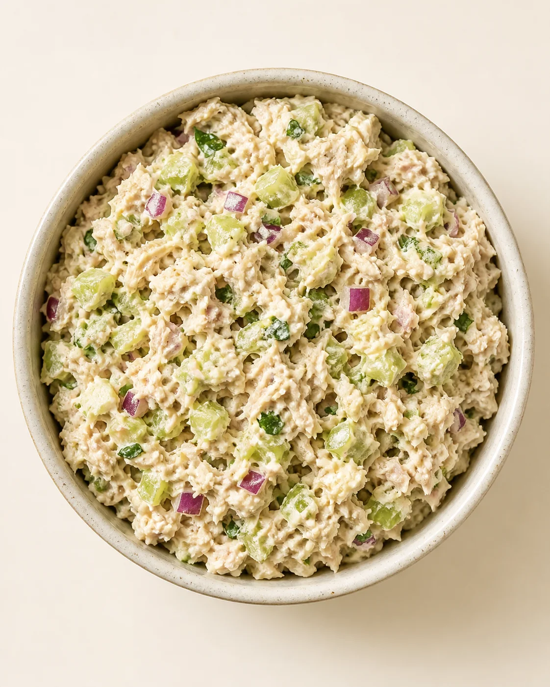 top-down view of a bowl of creamy chicken salad with diced celery and red onion.