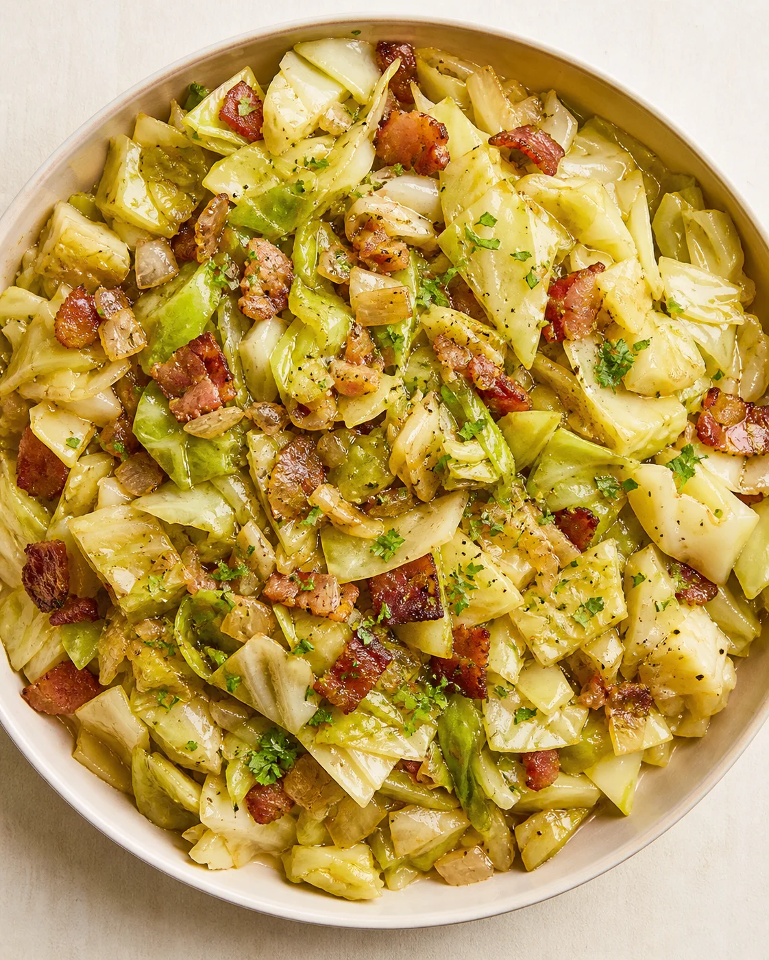 Top-down view of sautéed cabbage with crispy bacon in a round pan