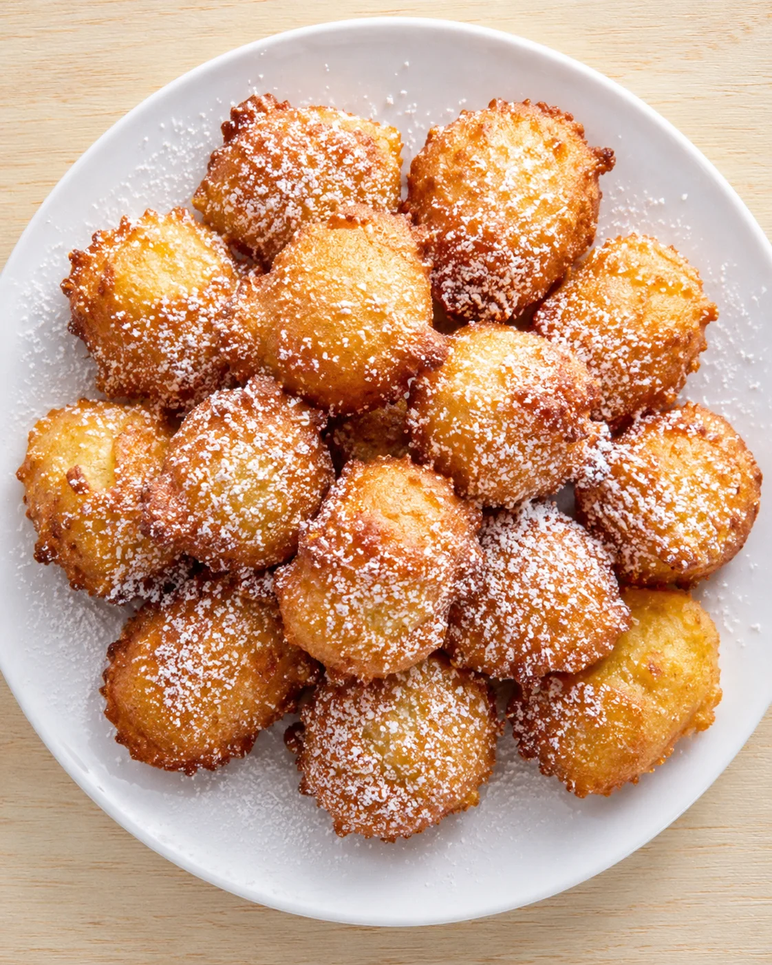 Plate of golden-brown fried dough bites dusted with powdered sugar