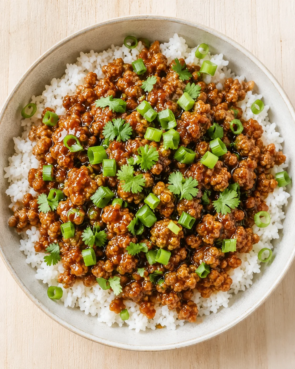 bowl of white rice topped with glossy ground-meat, cilantro, and green onions