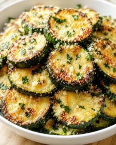 browned zucchini slices with melted cheese and parsley in a white bowl