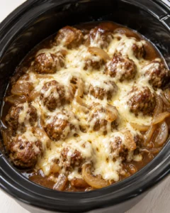 brown meatballs in a thick cheese-topped sauce inside a black slow cooker