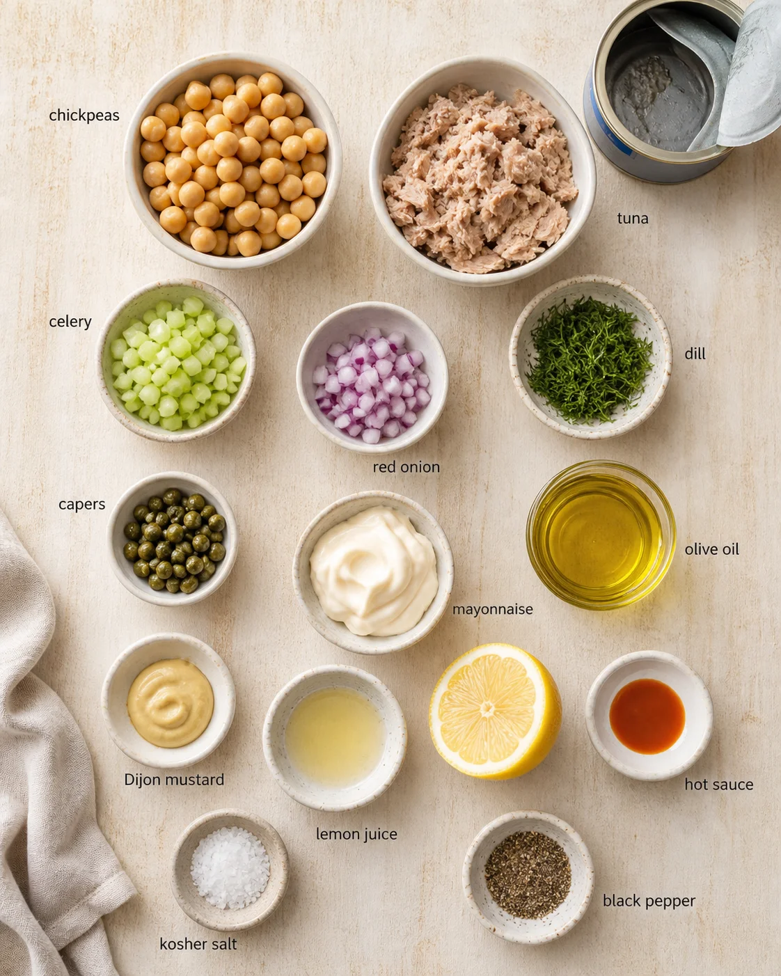 Overhead view of bowls with chickpeas, tuna, celery, red onion, dill, capers, and condiments.