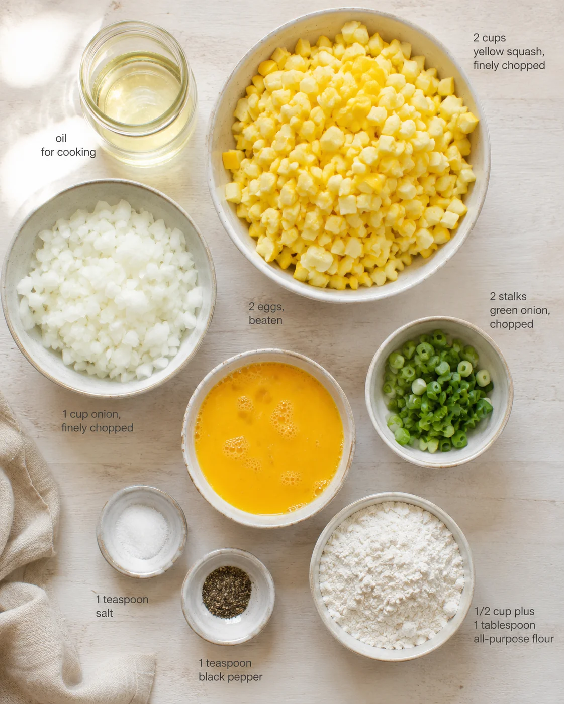 top-down view of bowls with chopped onions, yellow squash, green onions, beaten eggs, oil, and flour.